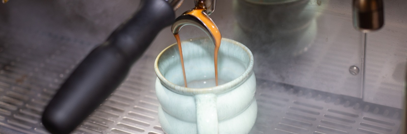 Espresso läuft aus der Siebträgermaschine in eine helle Tasse bei CIN CIN