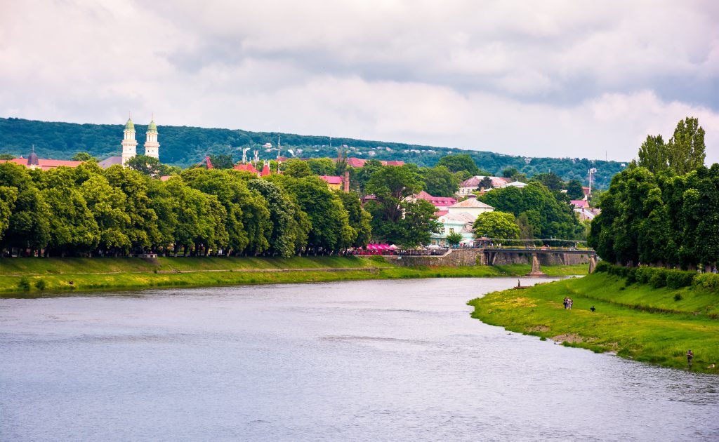 Fluss mit grünen Ufern und Stadtansicht im Hintergrund, Symbolbild für Passau Sehenswürdigkeiten abseits der üblichen Wege